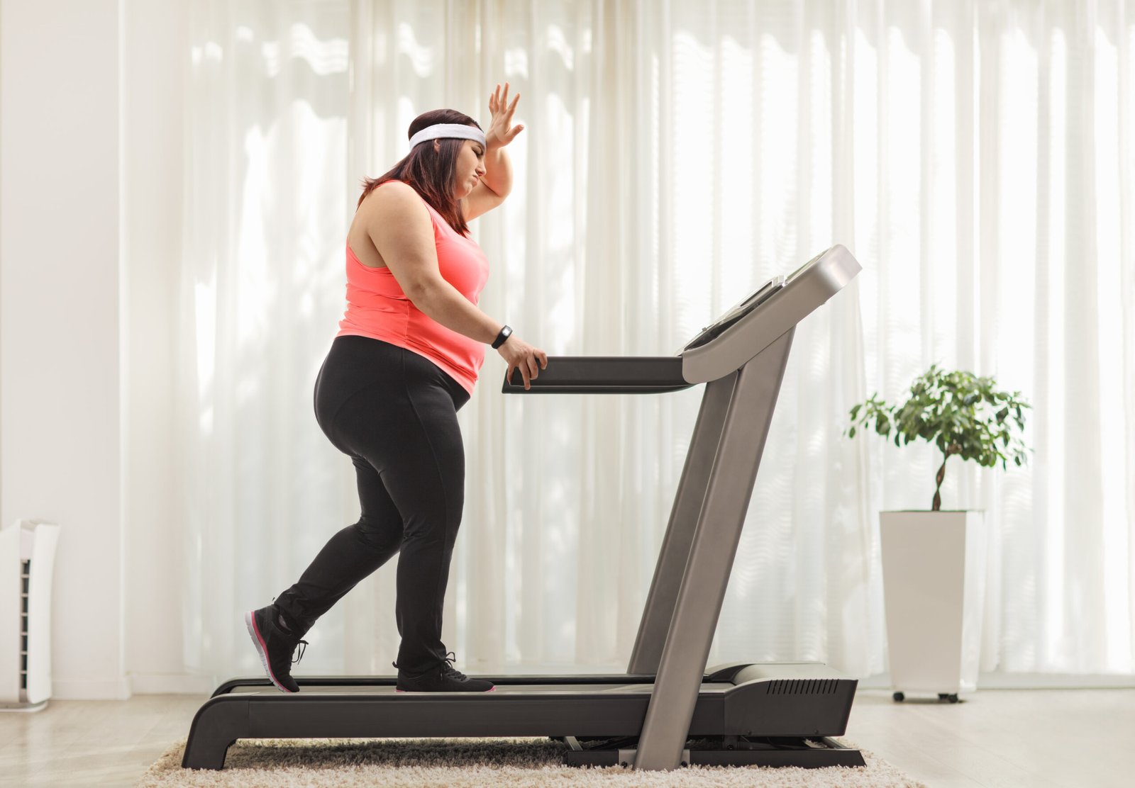 Tired overweight woman exercising on a treadmill at home