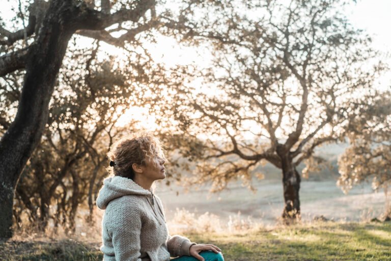 One woman sitting in outdoor leisure activity contemplating the nature around and enjoying autumn day alone. People female relaxing at the park in country side. Concept of serene person in daylight