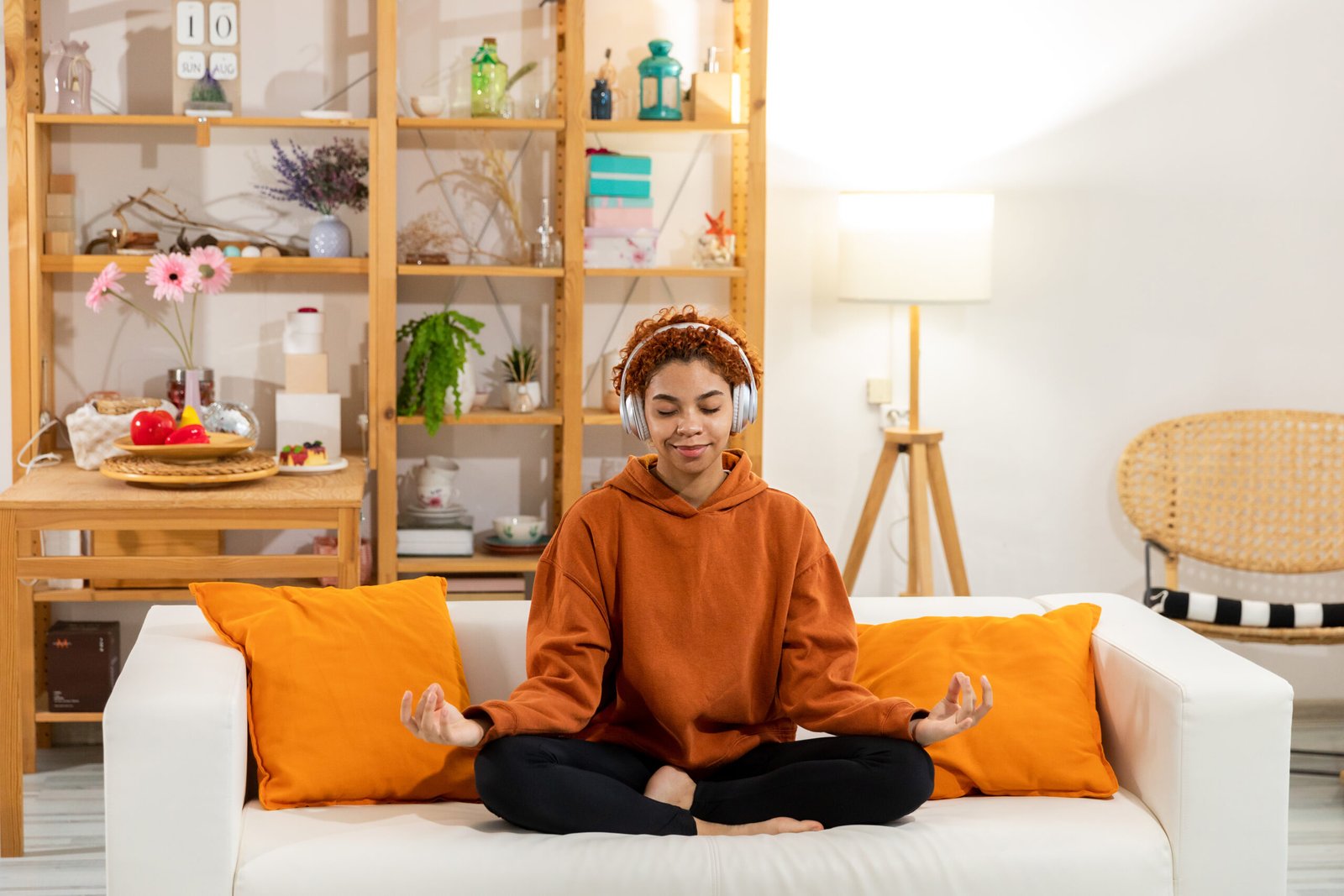 Yoga mindfulness meditation. Young healthy african girl practicing yoga at home. Woman sitting in lotus pose on yoga mat meditating smiling relaxing indoor. Girl doing breathing practice, yoga at home