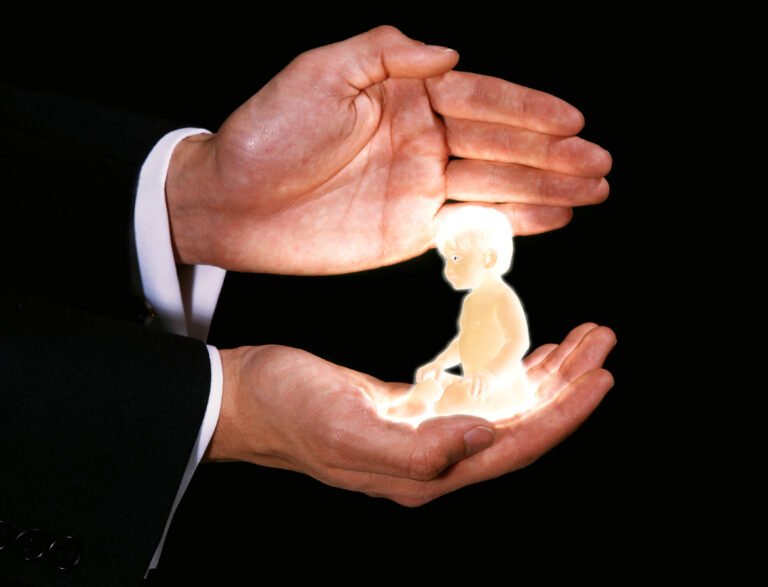 Man with a Baby in his Hands against Black Background