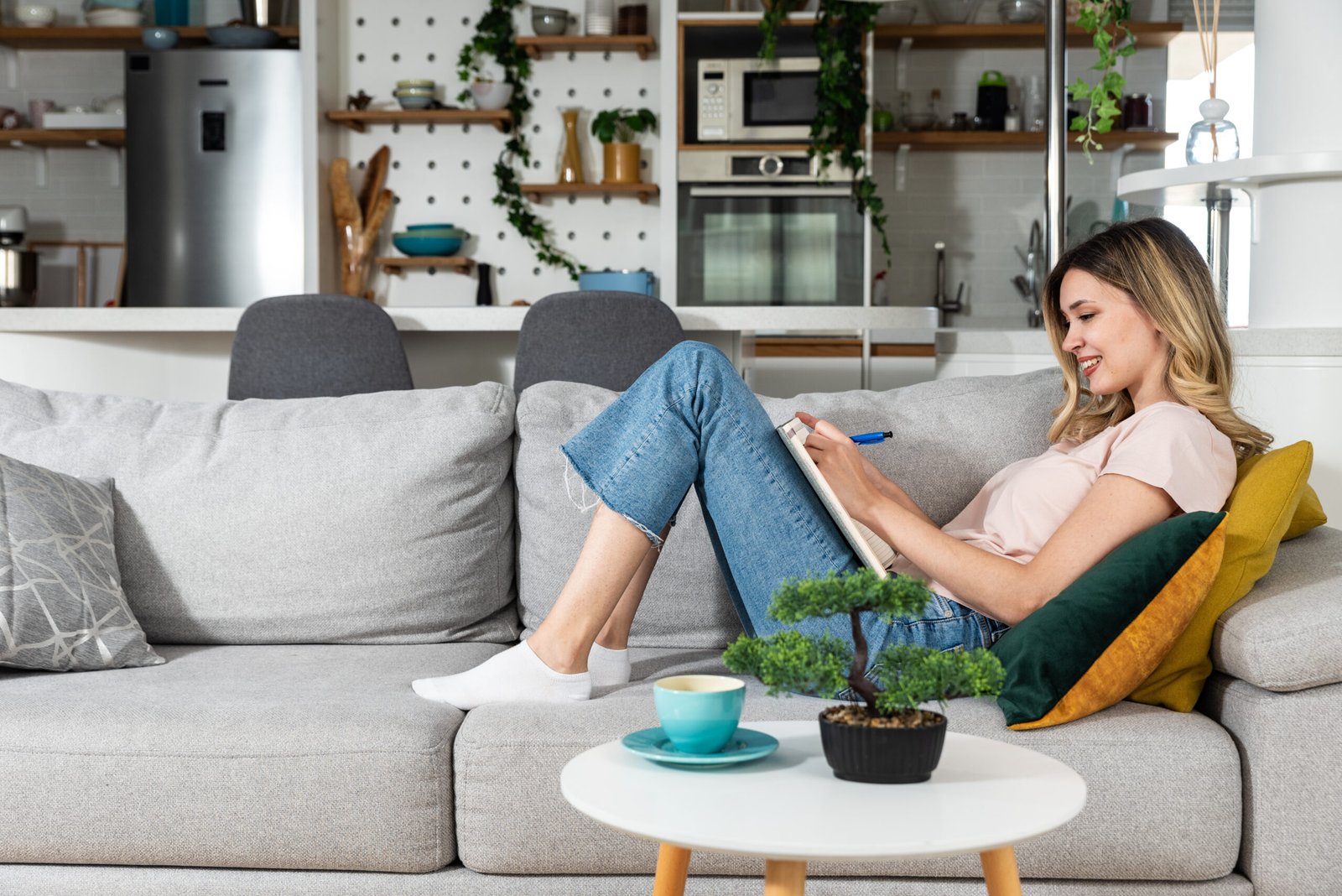 Young woman sitting on the sofa writing down the guest list of her friends whom she will invite to her bachelorette party for her wedding. Creative girl writes down ideas make a list of things to do