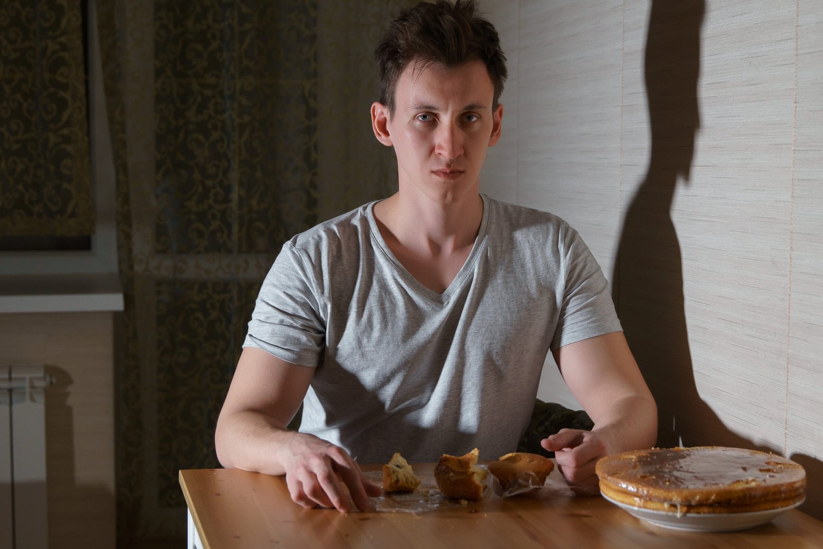 Young man eats sweets in the kitchen at night