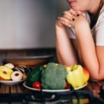 Woman choosing between sweets and healthy food