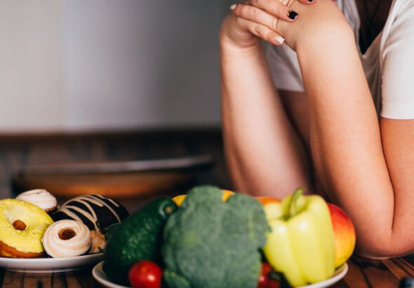 Woman choosing between sweets and healthy food